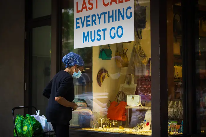 Woman peers into store window with sign that says, "Last Call: Everything Must Go."